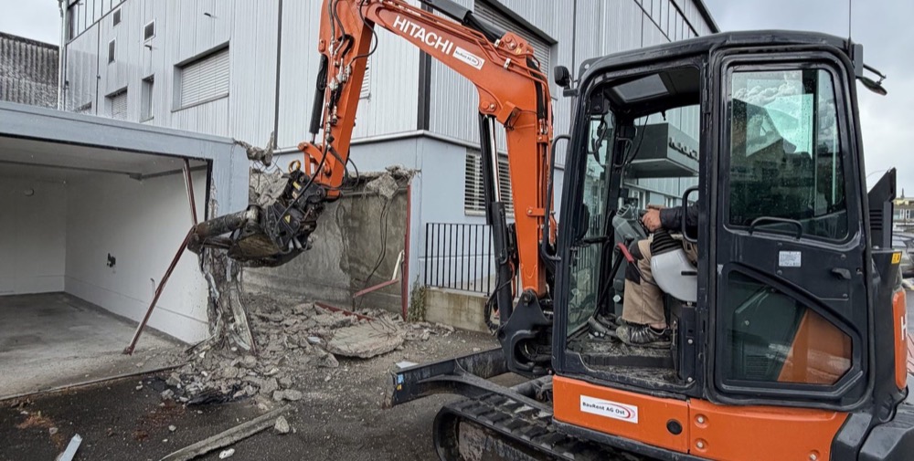 Oranger Minibagger mit Abbruchgreifer